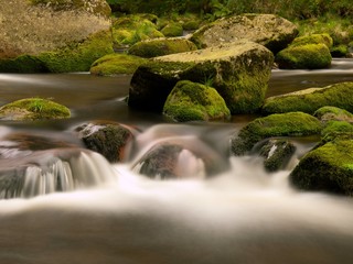 Autumn river with blurred waves, water run over boulders