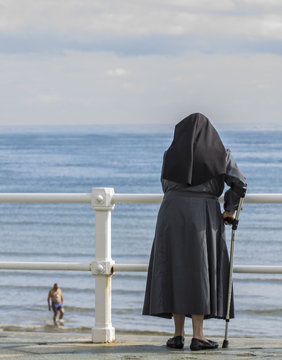 Monja con muleta mirando al mar