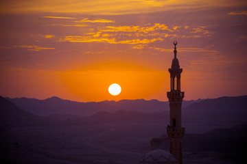 Sunset over desert with muslim mosque in the foreground