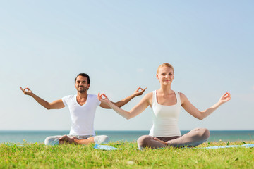 smiling couple making yoga exercises outdoors