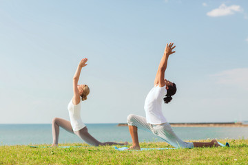 smiling couple making yoga exercises outdoors