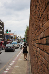 Fototapeta na wymiar Girl Walking Along A Wall On The Sidewalk