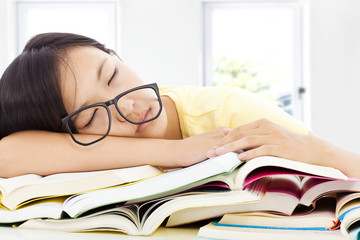 tired student girl with glasses sleeping on the books