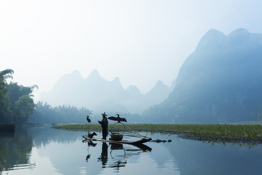 Fototapeta Cormorant, fish man and Li River scenery sight with fog in sprin
