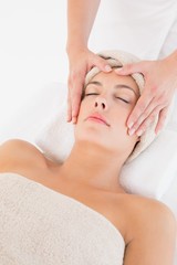 Obraz na płótnie Canvas Attractive young woman receiving facial massage at spa center