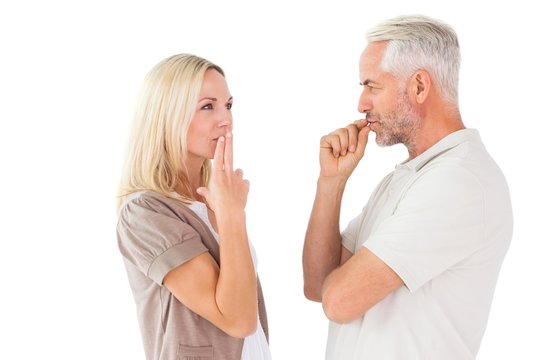 Couple staying silent with fingers on lips