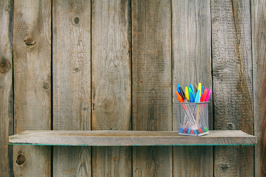Pens on a wooden shelf.