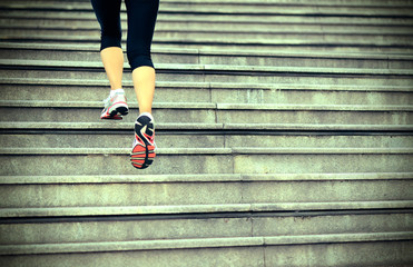 sports woman legs running up on stone stairs 