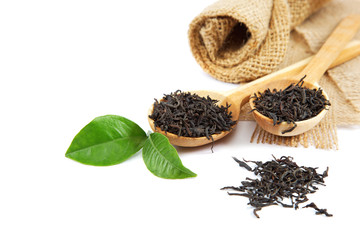 Black tea in a wooden spoon and green lemon leaves.