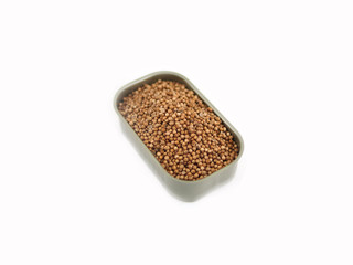 dried coriander seeds in can on white