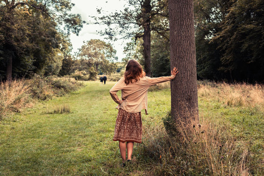 Young woman lesaning against a tree in the forest