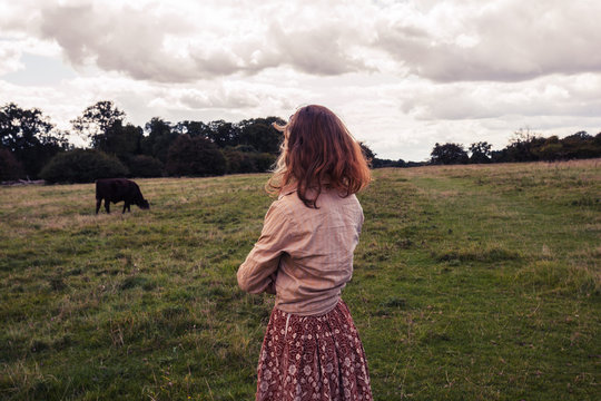 Young woman standing in field with cows