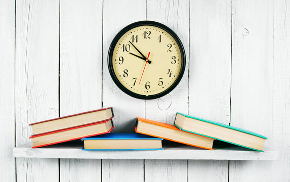Watches and books on a wooden shelf.