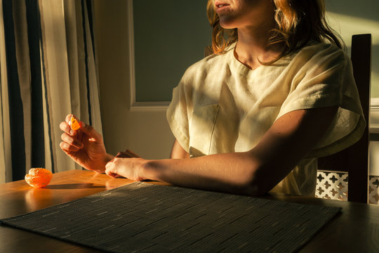 Young woman sitting at table with an orange