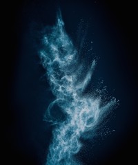 Blue powder exploding isolated on black