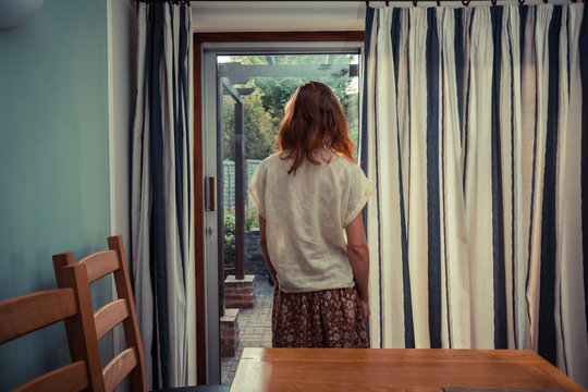 Young woman standing by curtains of french doors