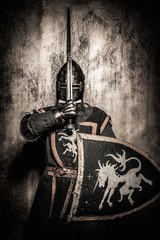 Medieval knight  holding sword in front of his face