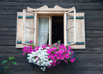 Fototapeta na wymiar window of a wooden hut decorated with flowers
