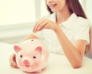 smiling child putting coin into big piggy bank