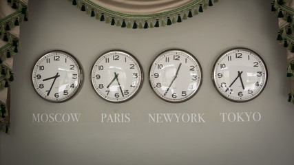 clocks on a wall with time zone of different country