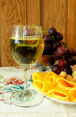 Glass of dry wine, cheese and a bunch of ripe grapes.