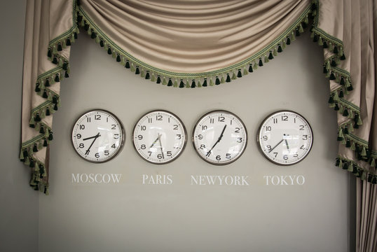 clocks on a wall with time zone of different country
