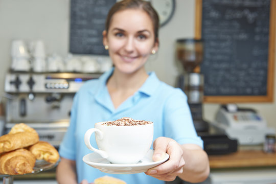 Waitress In Cafe Serving Customer With Coffee