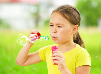 Little girl is blowing a soap bubbles