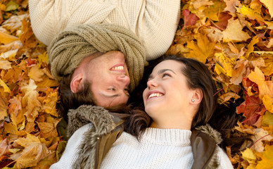 close up of smiling couple lying in autumn park