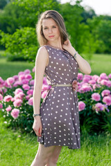 Nice young woman in the park near peonies