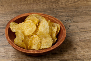 Crispy potato chips on wooden background