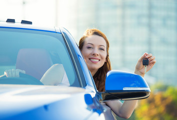 Happy, smiling woman, buyer sitting in her new car showing keys