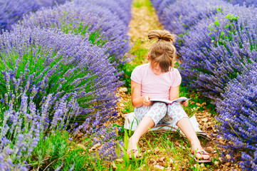 Adorable little girl reading a book in a lavender field