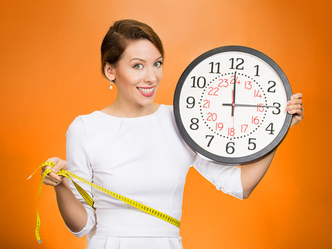 Happy Female holding clock, measuring her waist with tape