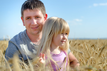 Cute little girl with her father in a wheat field