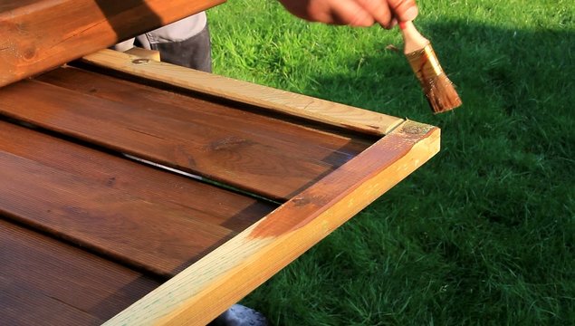 Zaun streichen mit Lasur auf Wiese