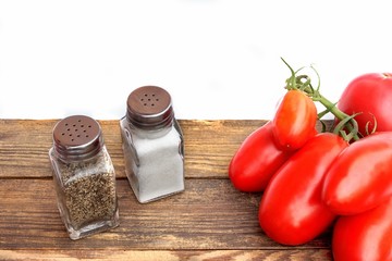 Fresh tomatoes and shakers on vintage wooden board