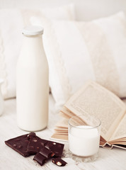 Still life interior details, glass of milk, chocolate and a book