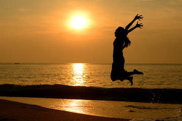 Fototapeta na wymiar Silhouette happy woman jumping on the beach