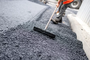 Fotobehang Worker leveling fresh asphalt on a road building © aboutmomentsimages