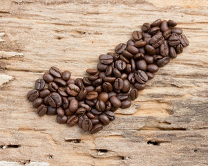 Checkmark from coffee beans on wood background
