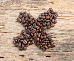 Checkmark from coffee beans on wood background
