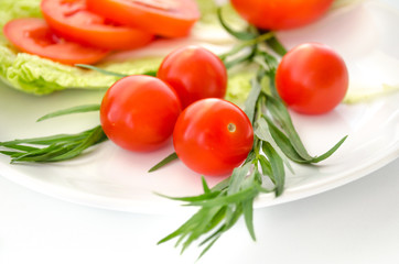 Tomatoes and green leaves on a white background