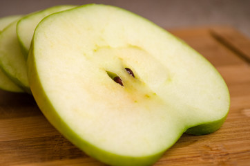 sliced green apple on wooden cutting board