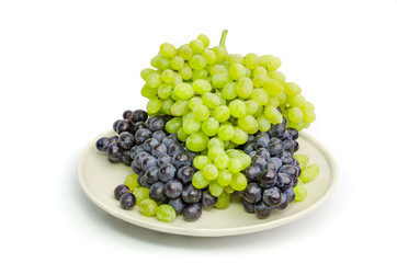 Black and green grapes bunches on white plate isolated on white