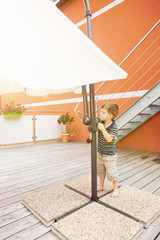 Kleiner Junge spannt den Sonnenschirm auf