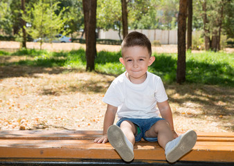 Cute little child boy in park on nature at summer.