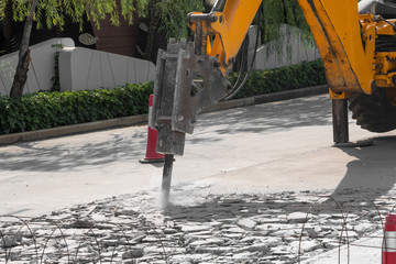 Excavator breaking and drilling concrete road for repairing