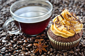 A cup of coffee and a muffin with coffee beans background