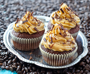 Muffins with caramel cream on coffee beans  background